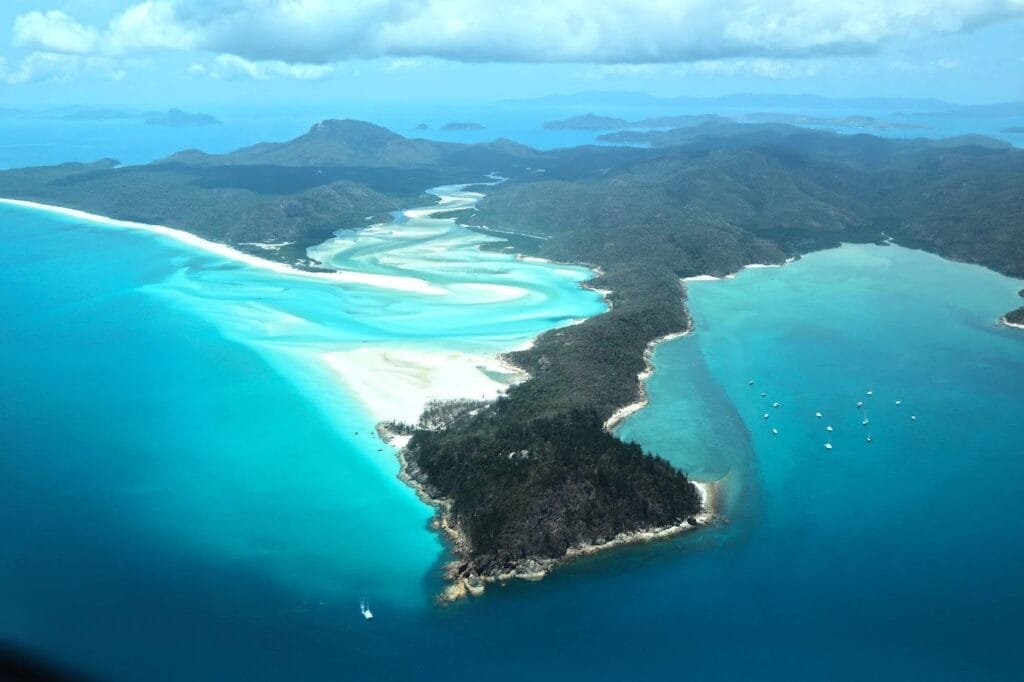 Vista panorâmica de Whitehaven Beach no Parque Nacional das Ilhas Whitsunday, Austrália, com areias brancas e águas translúcidas.